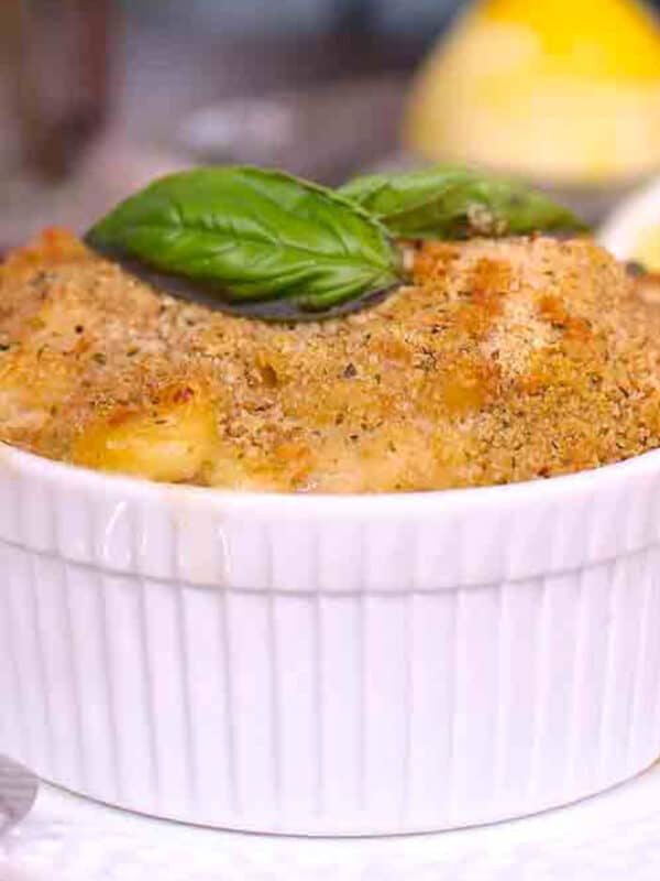 a small tuna casserole topped with bread crumbs and fresh basil on a white plate.