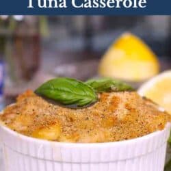 a small tuna casserole topped with bread crumbs and fresh basil on a white plate.