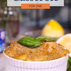 a small tuna casserole topped with bread crumbs and fresh basil on a white plate.
