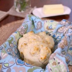 three drop biscuits on a blue napkin next to a plate of butter