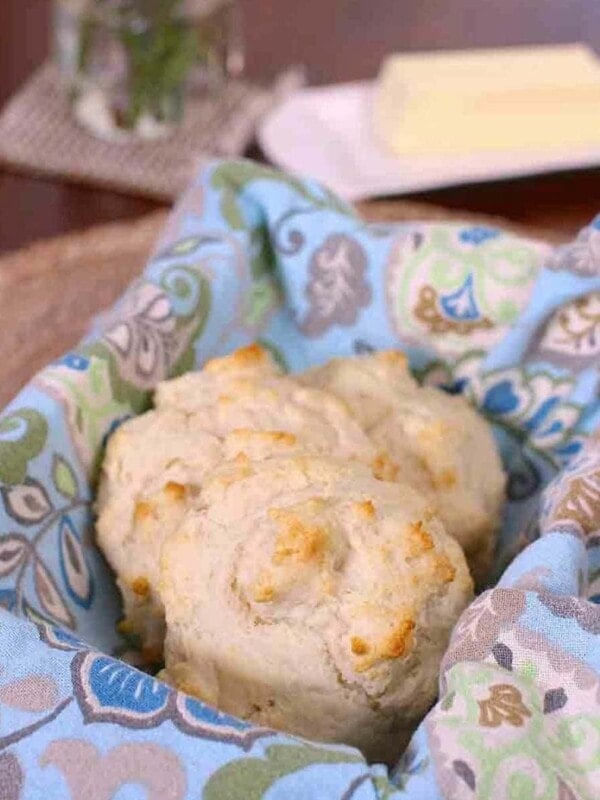 three drop biscuits on a blue napkin next to a plate of butter