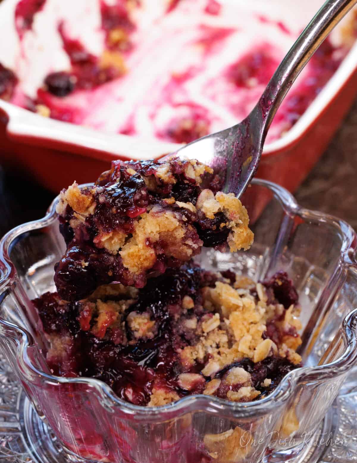 blueberry crumble in a small bowl with a spoon on the side