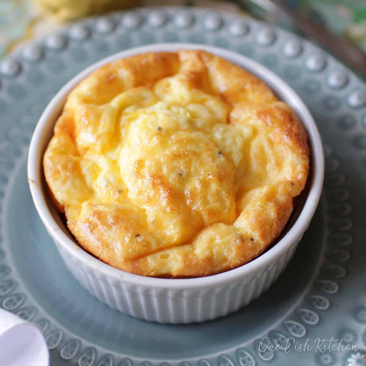 An overhead view of a small ramekin filled with baked eggs next to a small bowl of strawberries and a coffee mug.