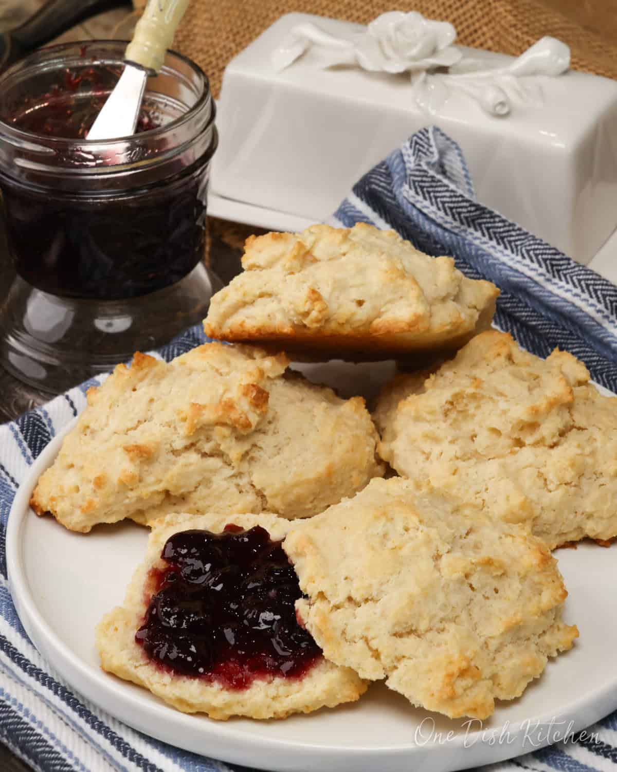 biscuits on a white plate sliced in half and topped with jam.