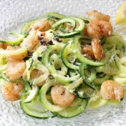 zucchini noodles on a plate with shrimp mixed in.