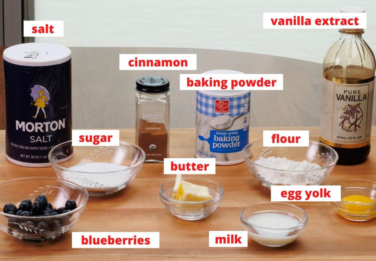 ingredients needed to make a small blueberry coffee cake on a wooden cutting board
