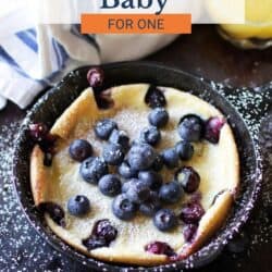 a mini Blueberry Dutch Baby in a skillet topped with powdered sugar.