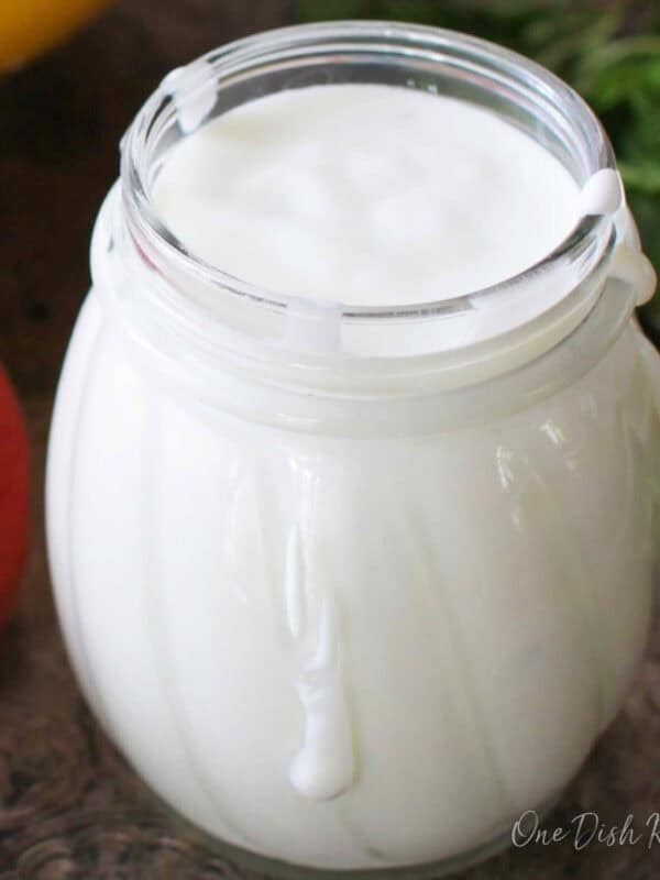 Small jar filled with creamy goat cheese salad dressing on a light surface.