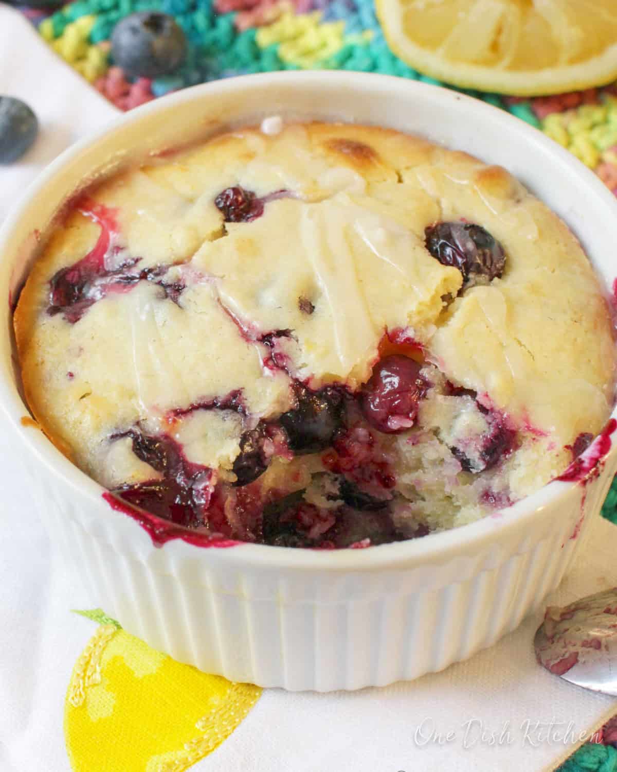 A closeup of a spoonful missing of lemon blueberry muffin filled with blueberries and a sugar lemon glaze.