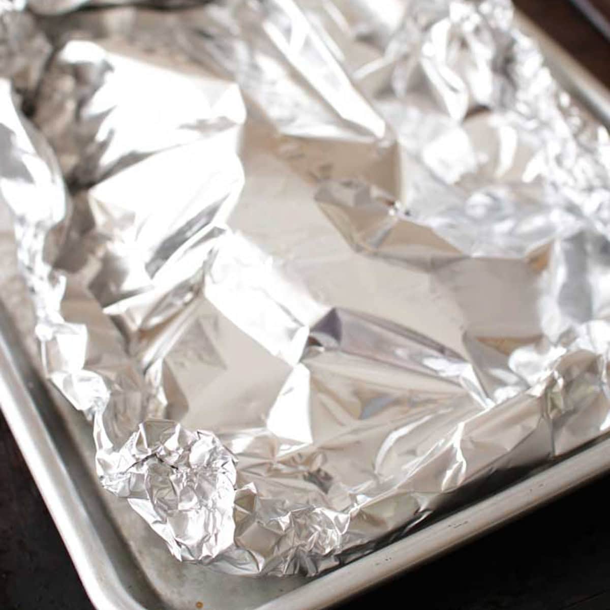 salmon wrapped in foil on a baking sheet before baking.