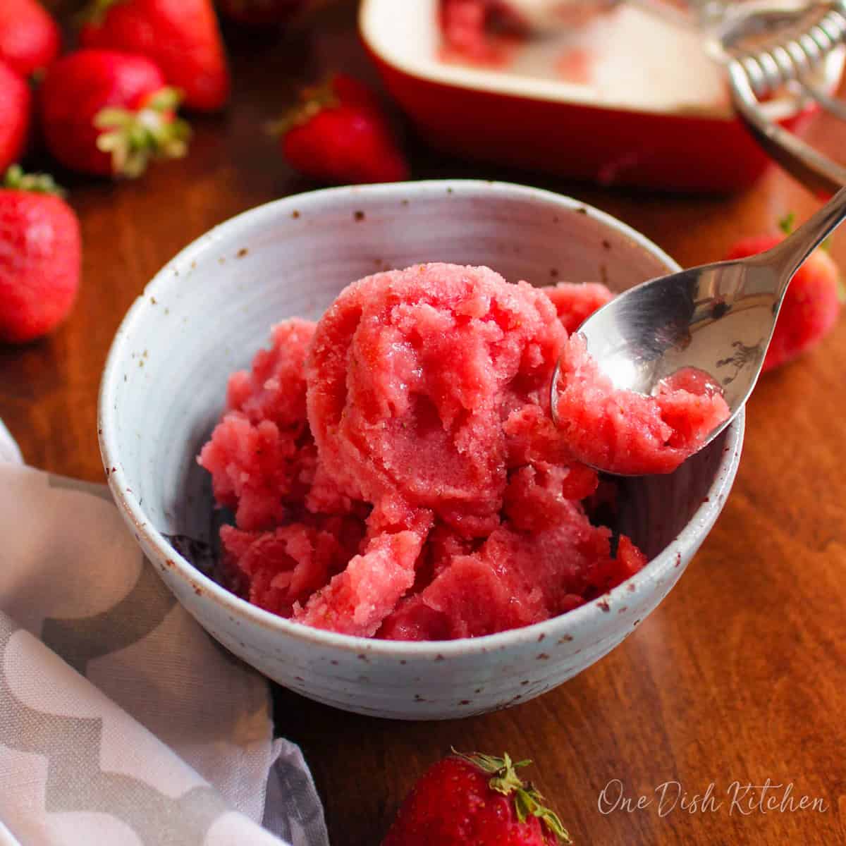 strawberry watermelon sorbet in a blue bowl with a spoon on the side.