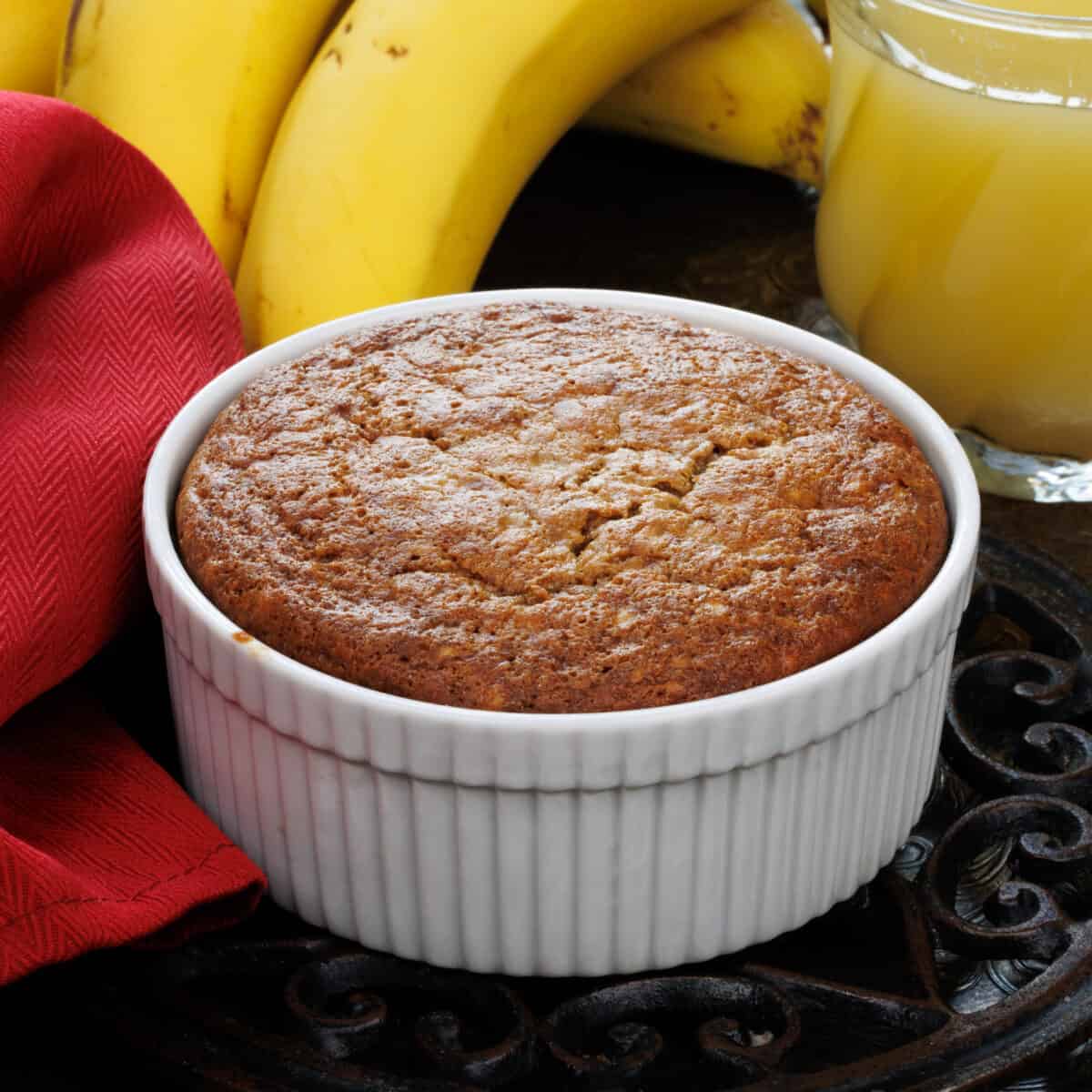 one small banana bread in a ramekin next to a red napkin