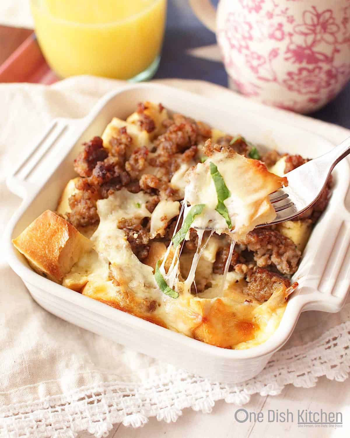 a small breakfast casserole on a table with a cup of coffee and a fork.
