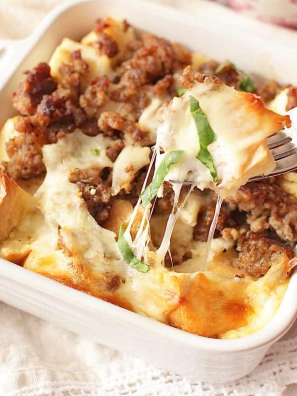 a small breakfast casserole on a table with a cup of coffee and a fork.