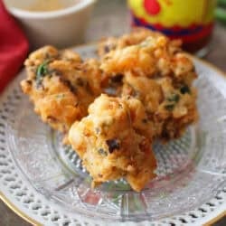 a small batch of crawfish beignets next to a jar of louisiana hot sauce.