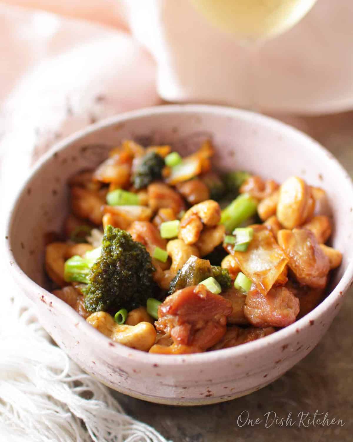 a single serving of cashew chicken in a bowl with tender chicken and broccoli in a garlic soy sauce.