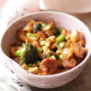 a single serving of cashew chicken in a bowl with tender chicken and broccoli in a garlic soy sauce.