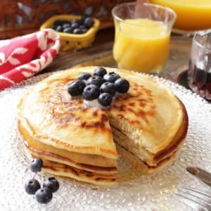 three pancakes on a plate with a fork on the side.