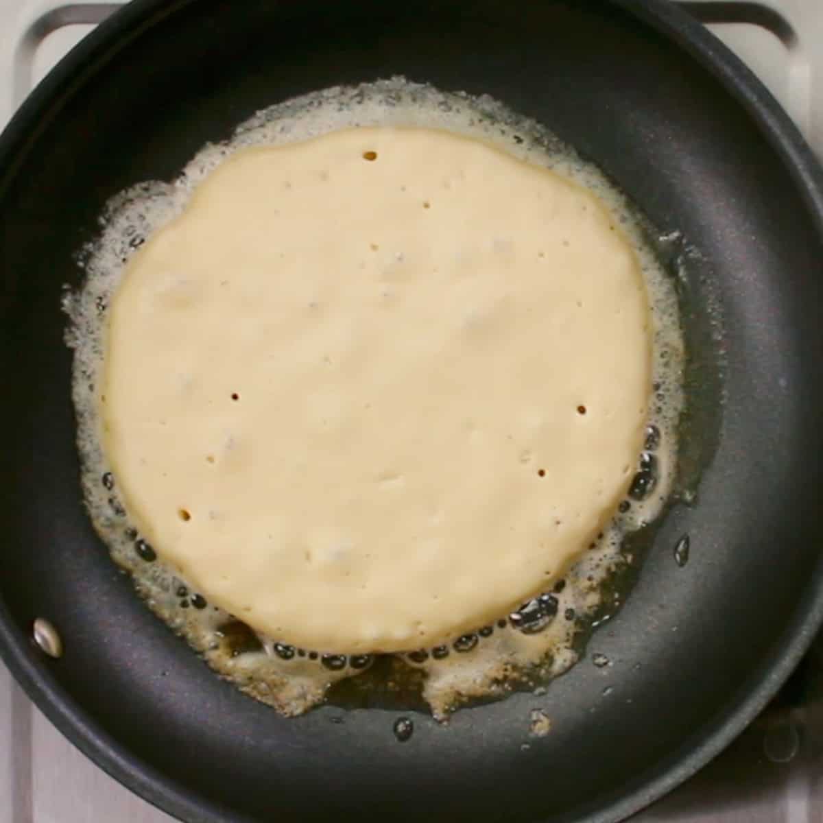 one pancake cooking in a skillet.