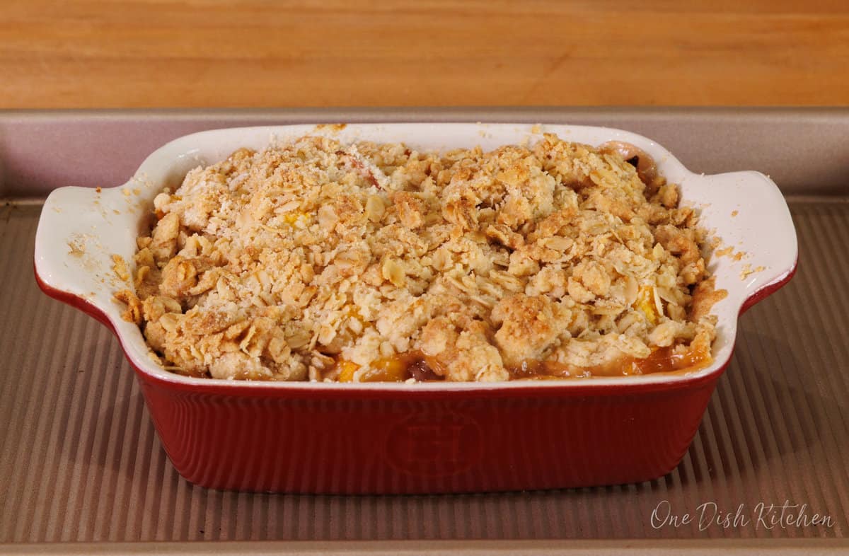 a peach crisp made with two peaches on a baking sheet