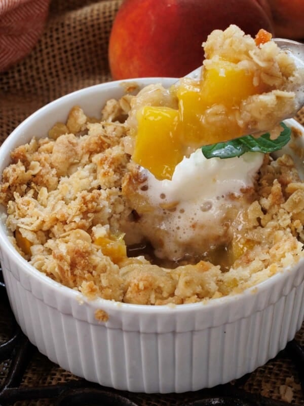 a spoonful of peach crisp next to a bowl