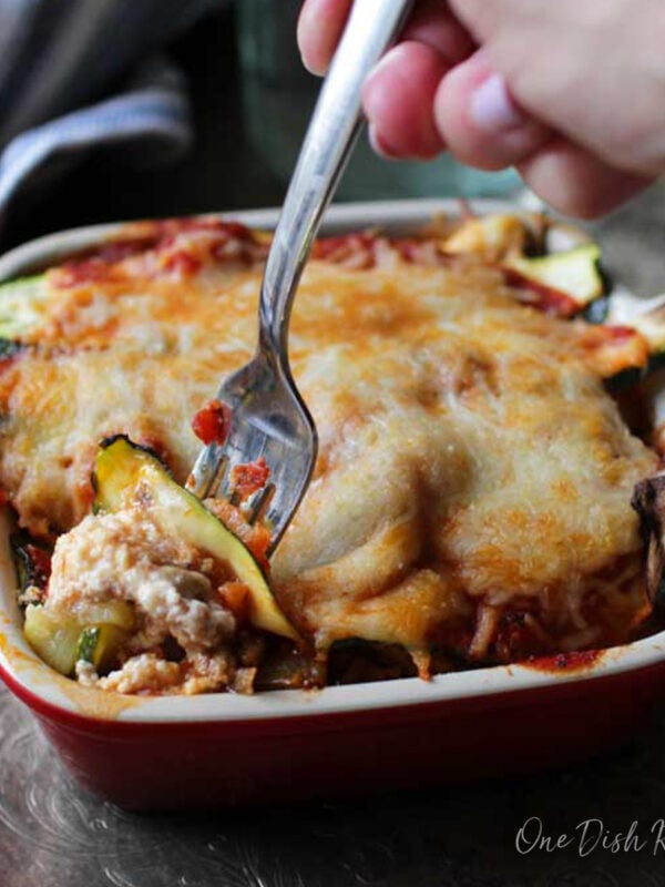 Baked Zucchini Lasagna in a square baking dish with fork taking a bite out.