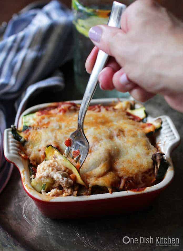 Baked Zucchini Lasagna in a square baking dish with fork taking a bite out