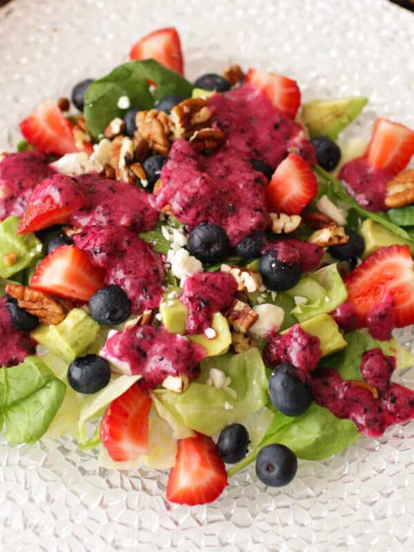 an avocado salad topped with blueberry vinaigrette on a white plate.