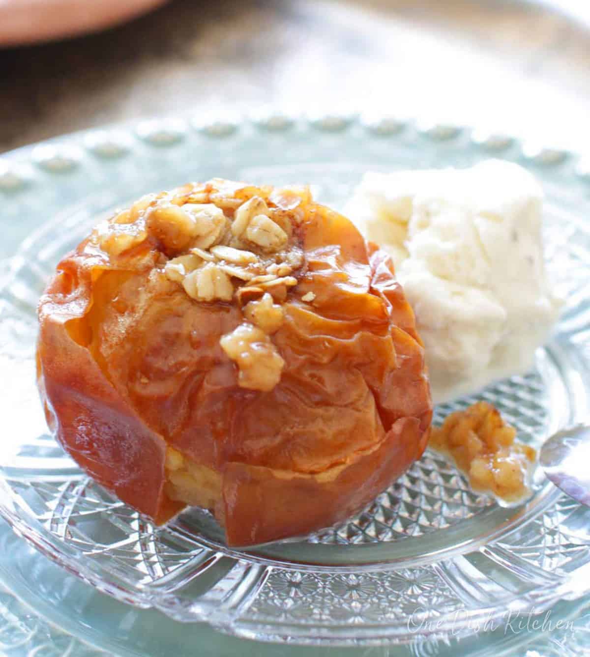 a single baked apple on a plate with a scoop of vanilla ice cream.