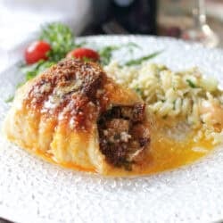 Single serving baked stuffed fish rolled and baked in a small dish, filled with bacon and vegetable stuffing and topped with Parmesan cheese, ready to serve.
