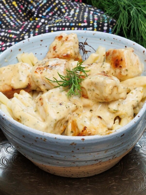 chicken in mustard sauce in a blue bowl over pasta