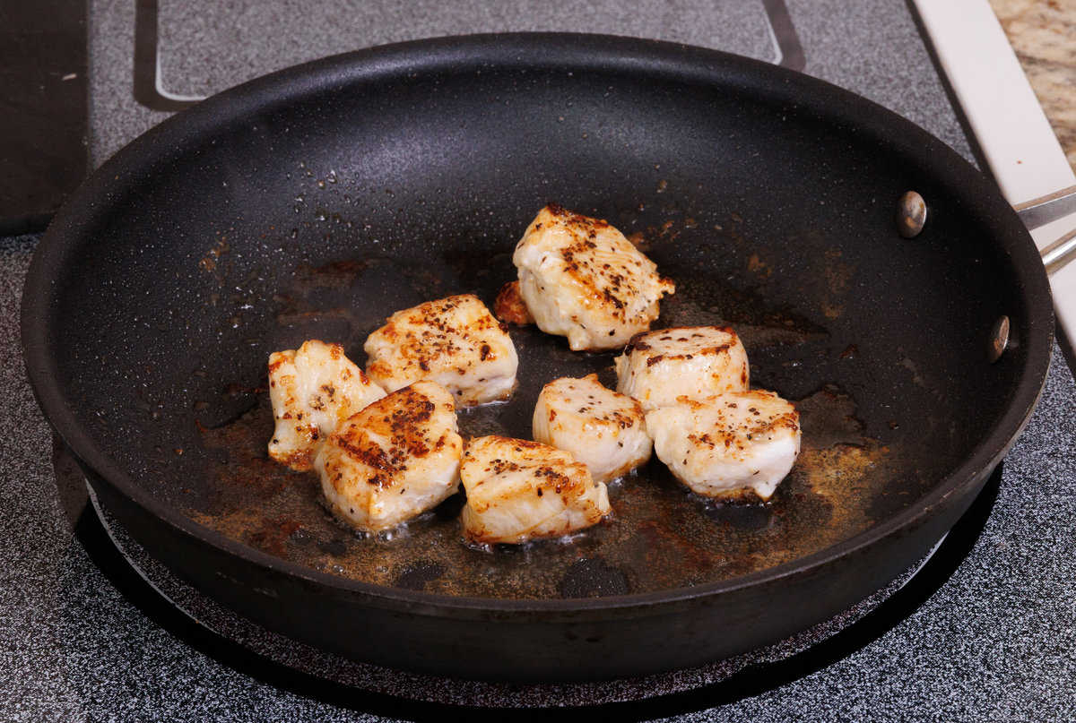 chicken cooking in a black skillet.