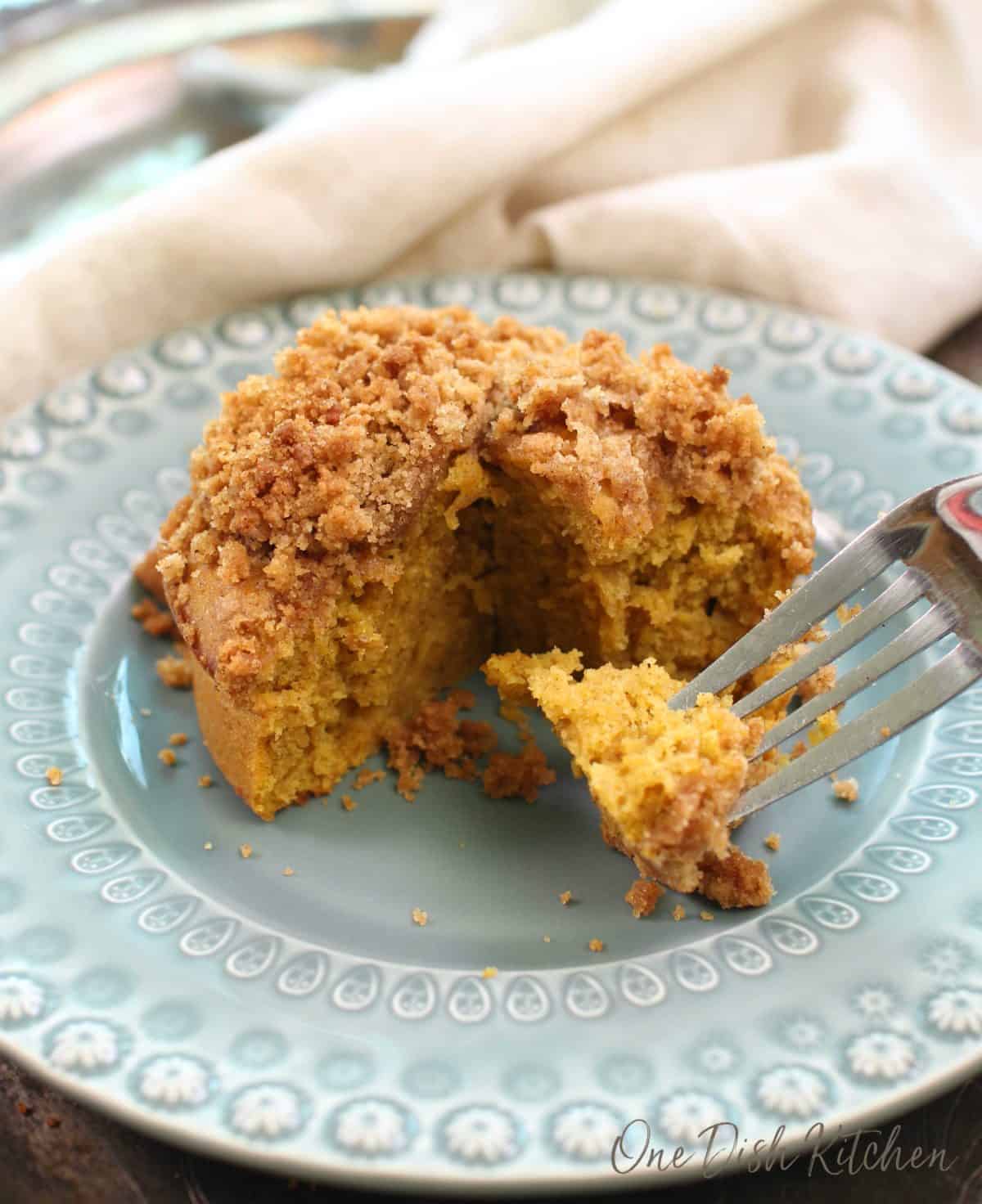 a round pumpkin coffee cake on a blue plate with a piece of the cake on a fork.