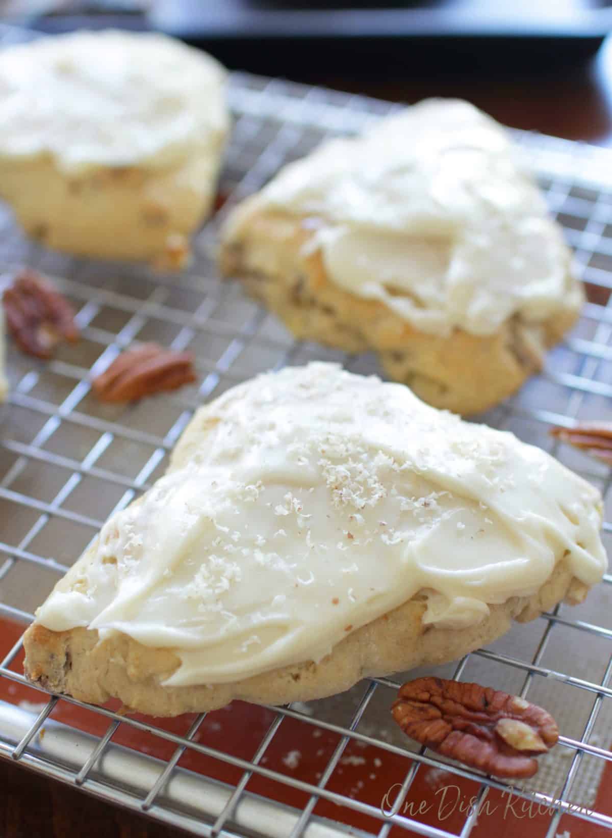 three frosted scones on a cooling rack.
