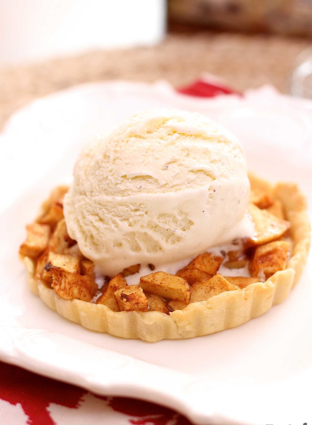 a small apple pie on a white plate topped with ice cream.