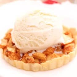an individual apple pie on a white plate.