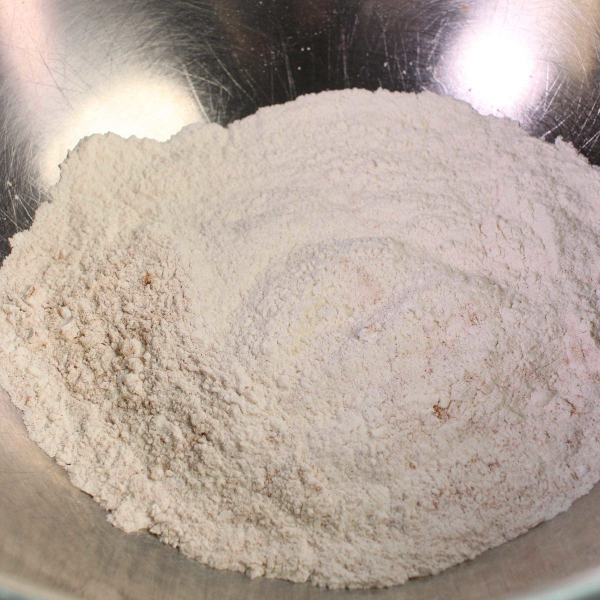 a silver mixing bowl filled with flour.