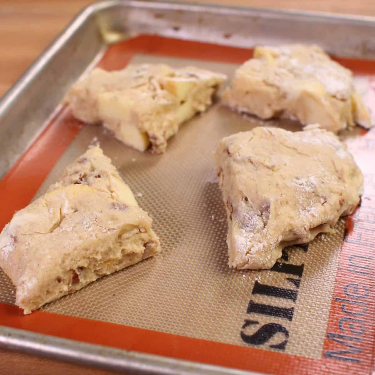 4 apple scones on a small baking sheet.