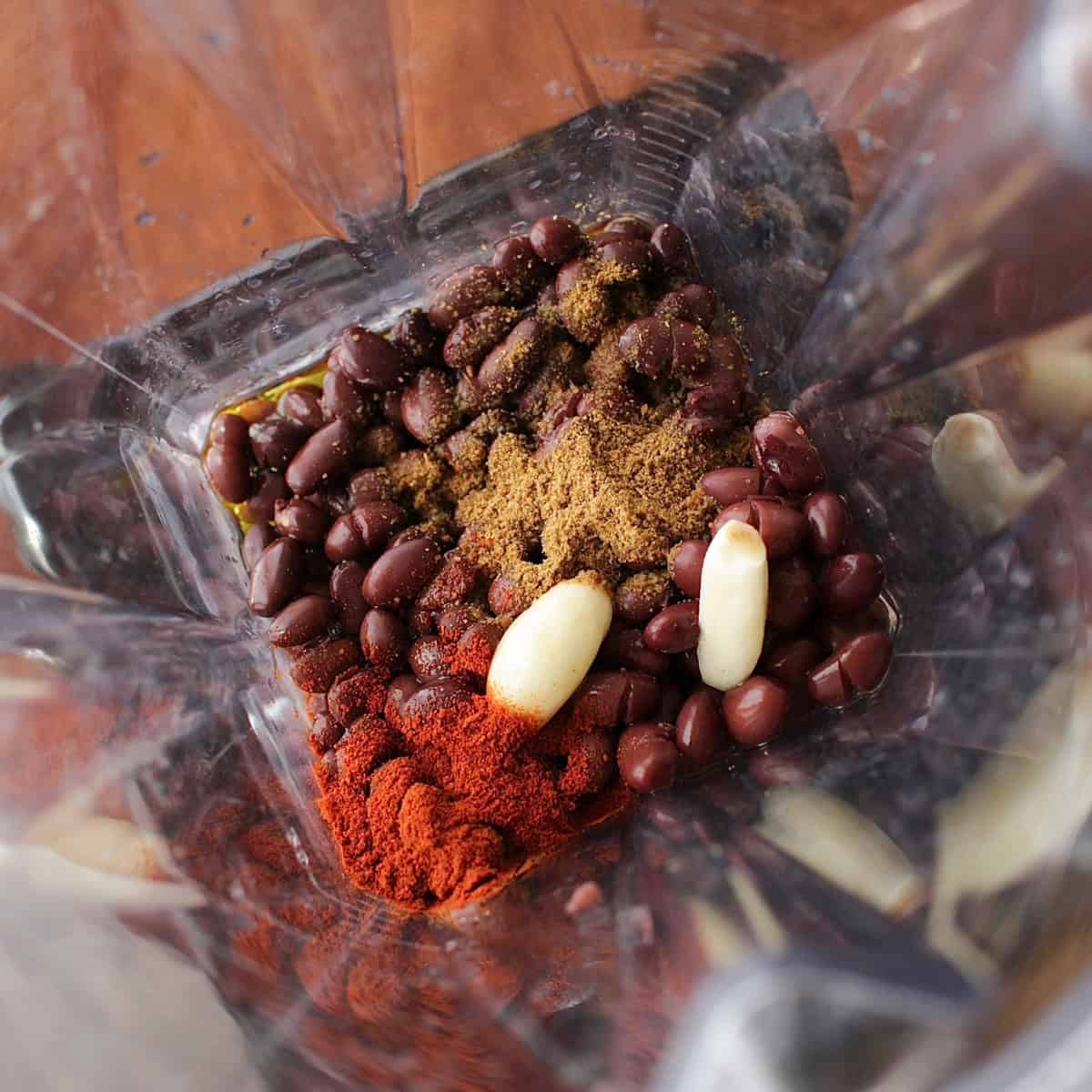 black bean hummus ingredients including canned black beans, garlic, and olive oil in a blender.