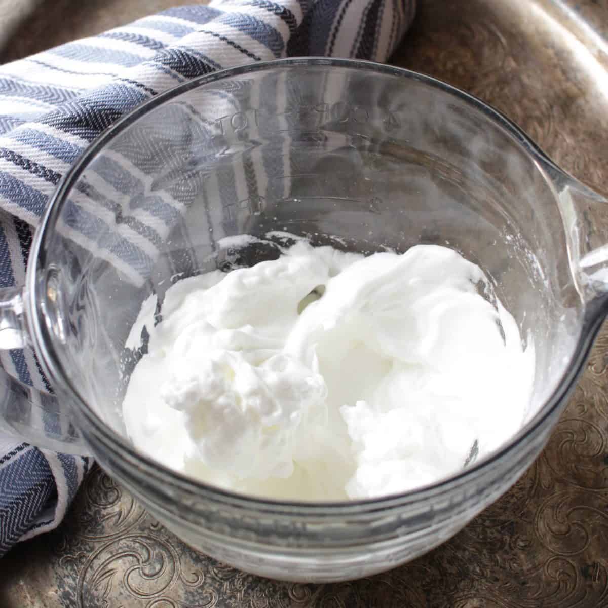 a bowl of whipped egg whites on a silver tray.
