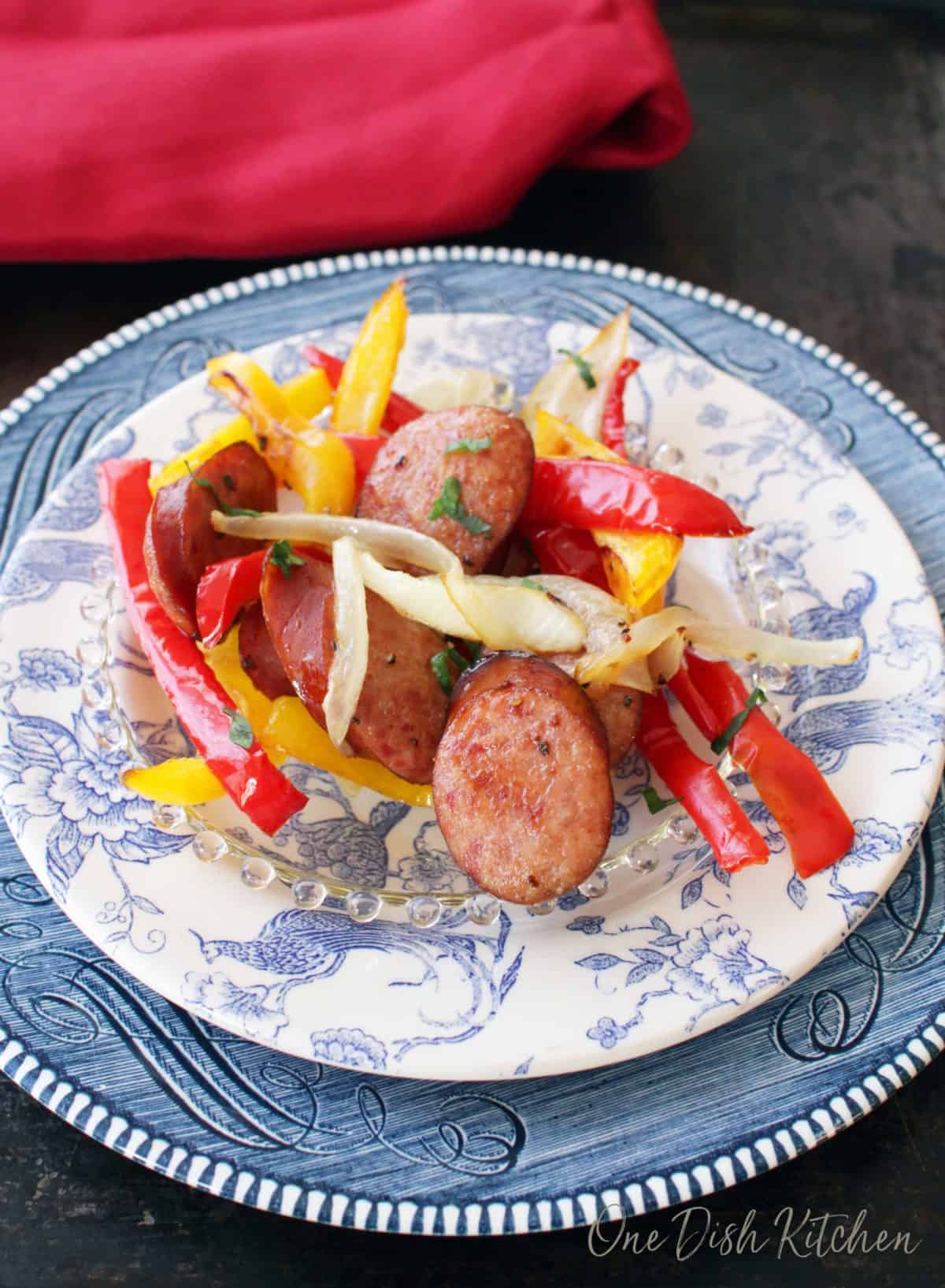 Sliced roasted sausage, red and yellow peppers, and onions on a plate.