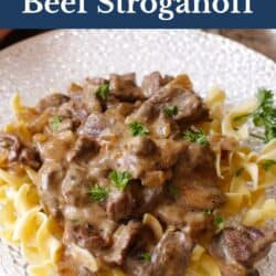 a plate filled with beef stroganoff topped with chopped parsley.