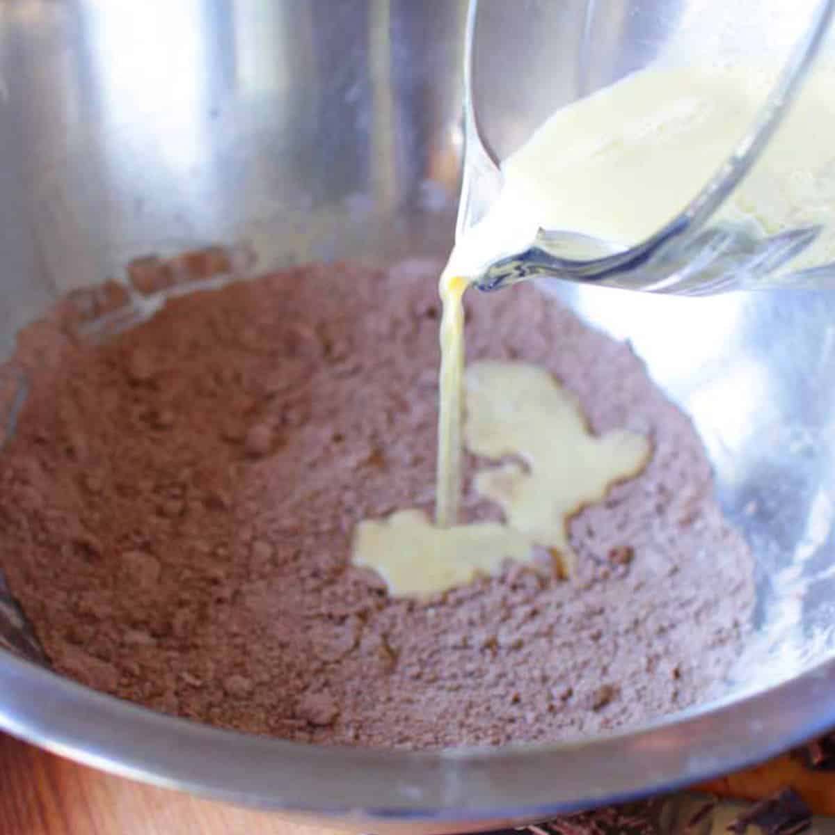 pouring milk into the dry ingredients in a mixing bowl for scones.