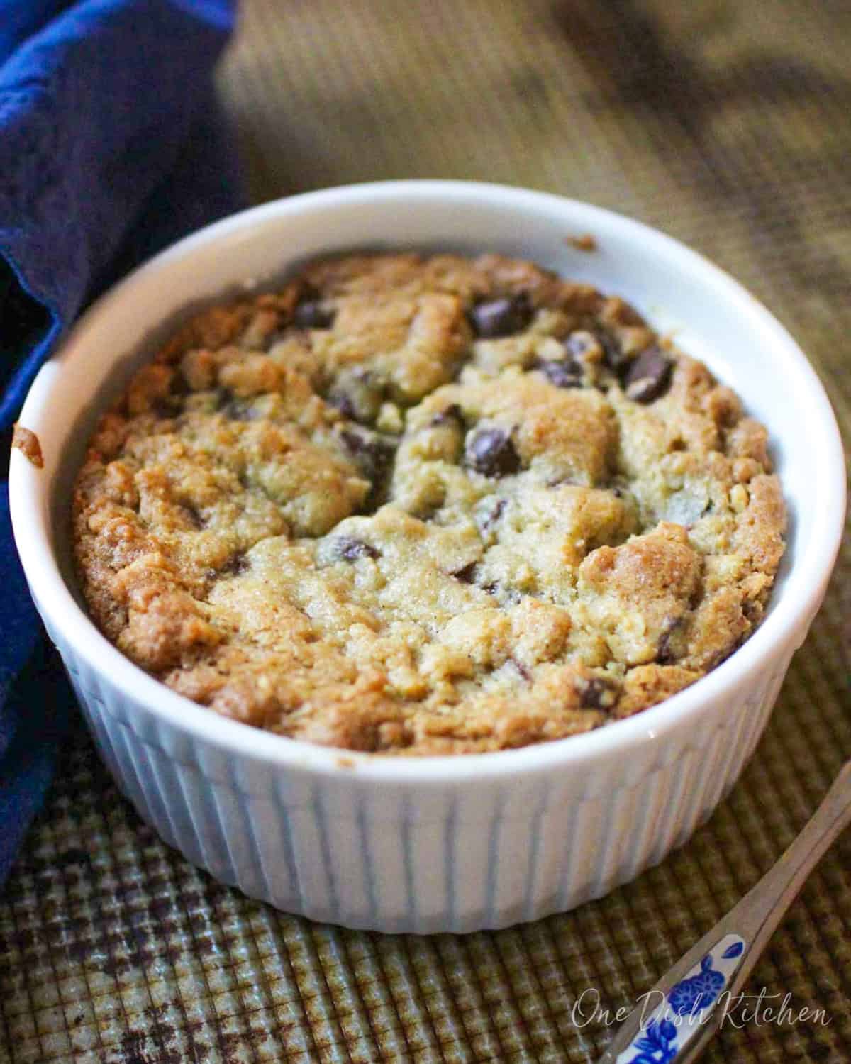 A deep dish chocolate chip cookie baked in a ramekin.