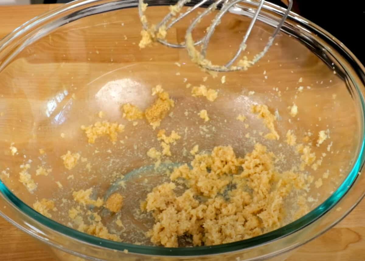softened butter and sugar mixing together in a mixing bowl with an electric beater on the side.