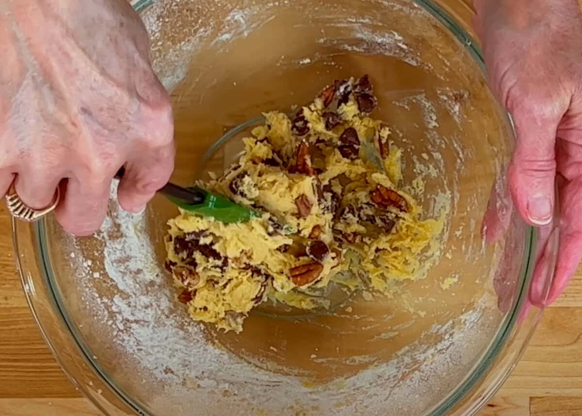 folding chocolate chips and nuts into cookie dough.