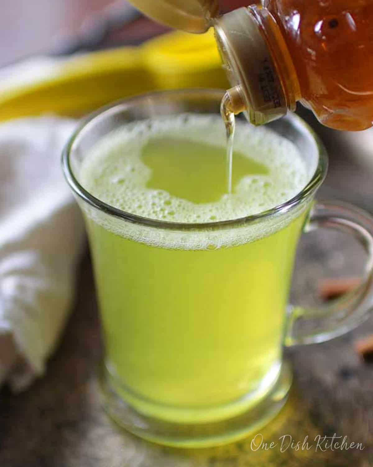 Pouring honey into turmeric tea on a metal tray.