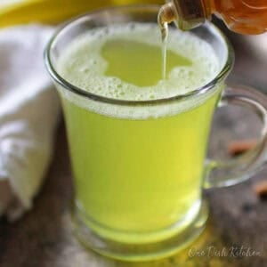 Pouring honey into turmeric tea on a metal tray.