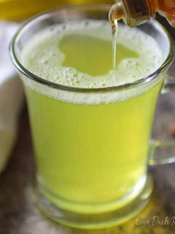 Pouring honey into turmeric tea on a metal tray.