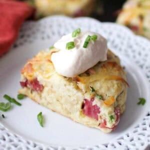 a ham and cheese scone topped with horseradish cream on a white plate.